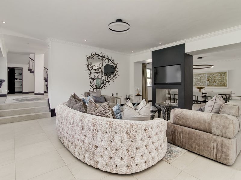 Spacious open-plan living area featuring a modern double-sided fireplace, elegant crown molding, and high-quality tiled flooring with seamless flow to the dining space.