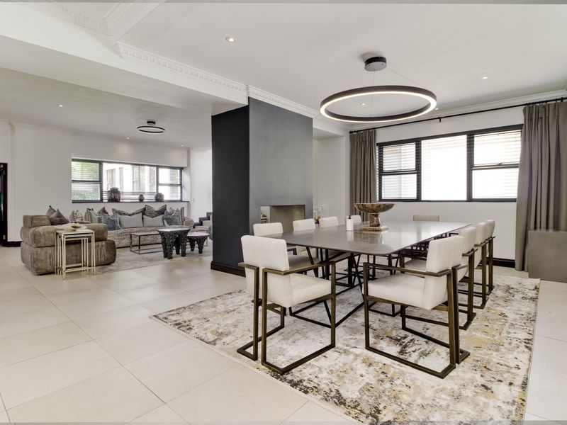 Spacious open-plan living and dining area featuring modern tiled flooring, elegant crown molding, and a central built-in fireplace.