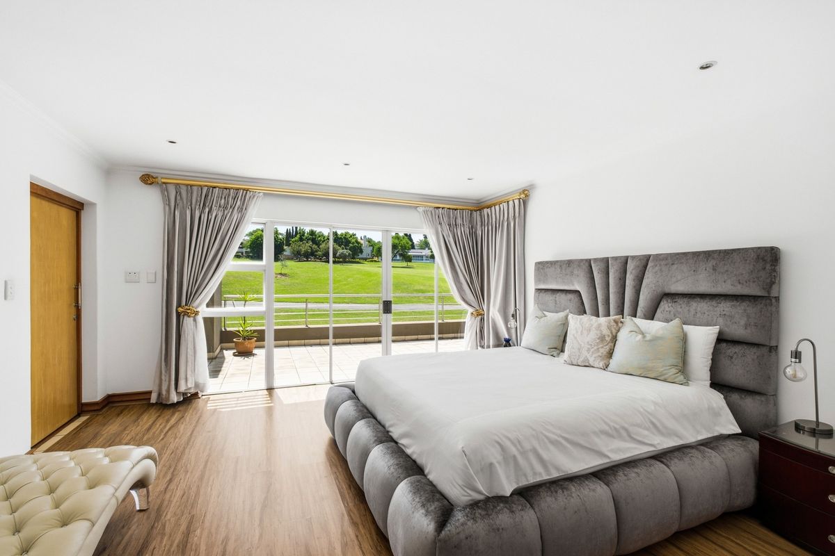 Spacious bedroom featuring laminate flooring, recessed lighting, and large sliding glass doors providing direct access to a private balcony with scenic views.