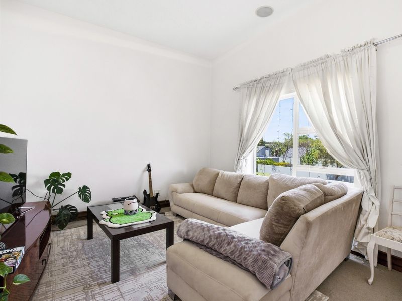 A bright and comfortable living room featuring neutral walls, carpeted flooring, and a large window that allows for ample natural light.