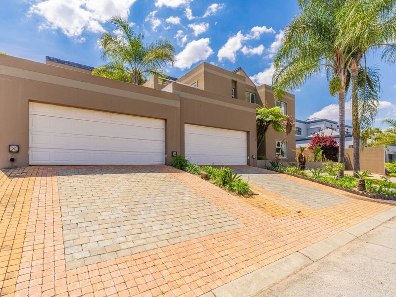 Modern double-story residence featuring a double garage, paved driveway, and well-maintained exterior facade with established landscaping.