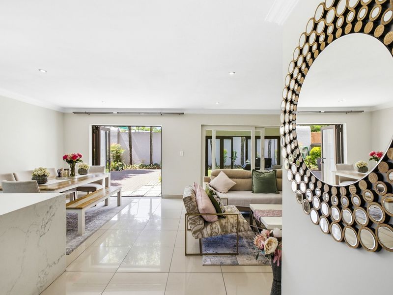 Spacious open-plan living and dining area featuring polished porcelain tiles, recessed lighting, and seamless bi-fold door access to the outdoor patio.