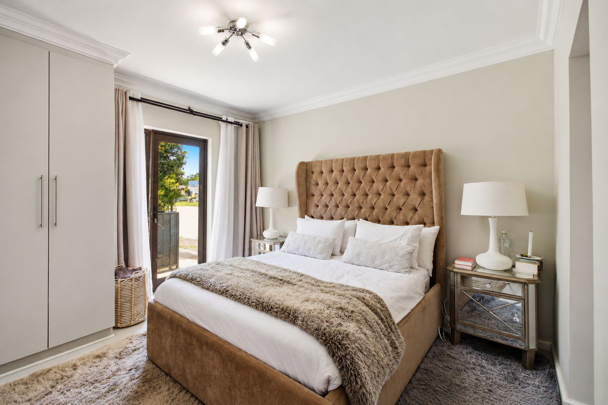 A well-maintained bedroom featuring built-in wardrobes, decorative ceiling cornicing, and a glass door providing access to the exterior.