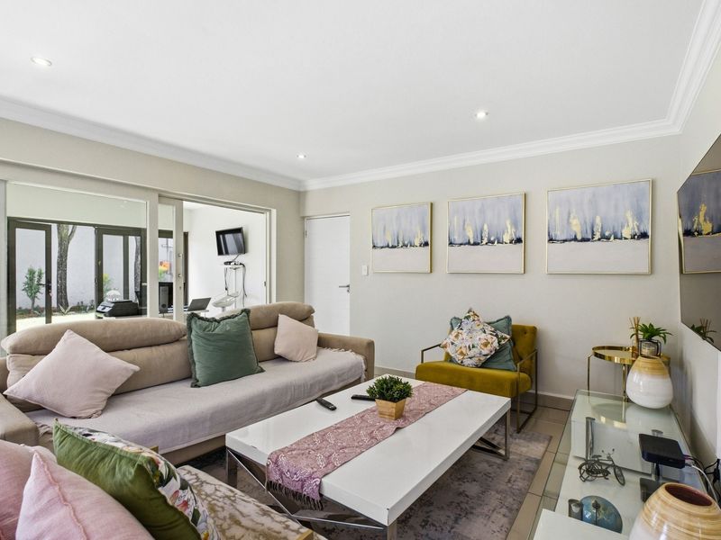 A bright and well-maintained living room featuring tiled flooring, recessed downlighting, and large sliding glass doors providing access to the outdoor area.
