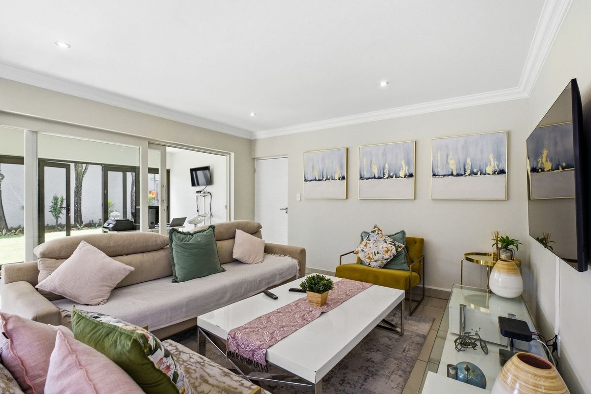 A bright and well-maintained living room featuring tiled flooring, recessed downlighting, and large sliding glass doors providing access to the outdoor area.
