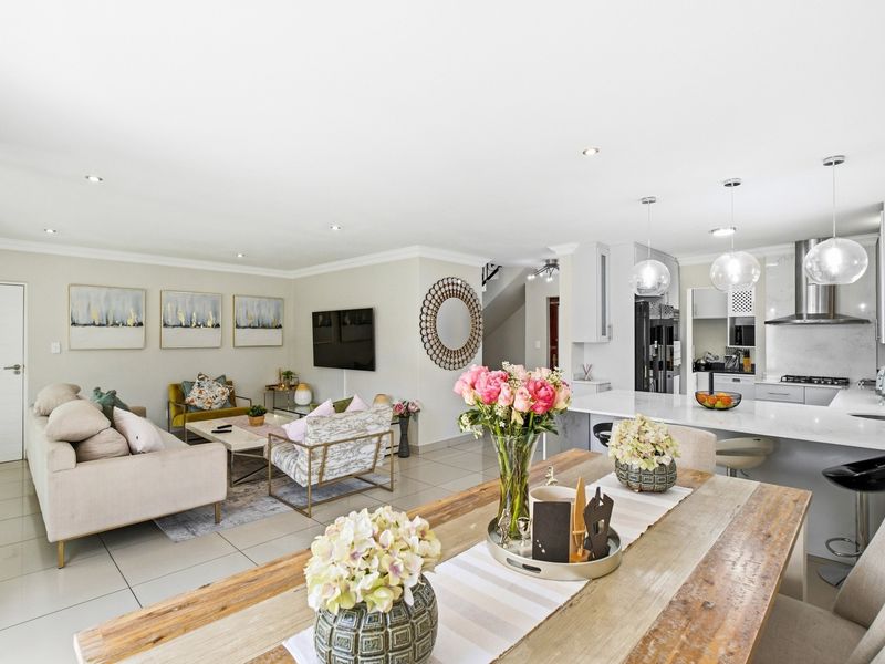 Spacious open-plan living area featuring a modern kitchen with stone countertops, a central island, and sleek tiled flooring throughout the dining and lounge space.