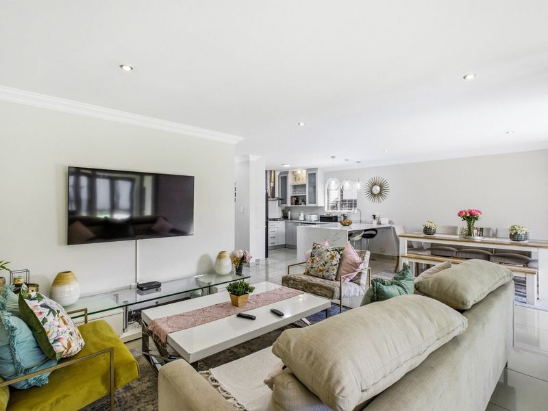 Spacious open-plan living, dining, and kitchen area featuring modern finishes, recessed lighting, and sleek tiled flooring throughout.