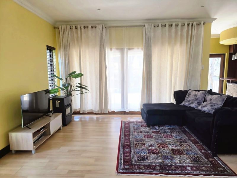 A bright living room featuring light laminate flooring, recessed ceiling lighting, and large sliding glass doors that provide access to the outdoor area.