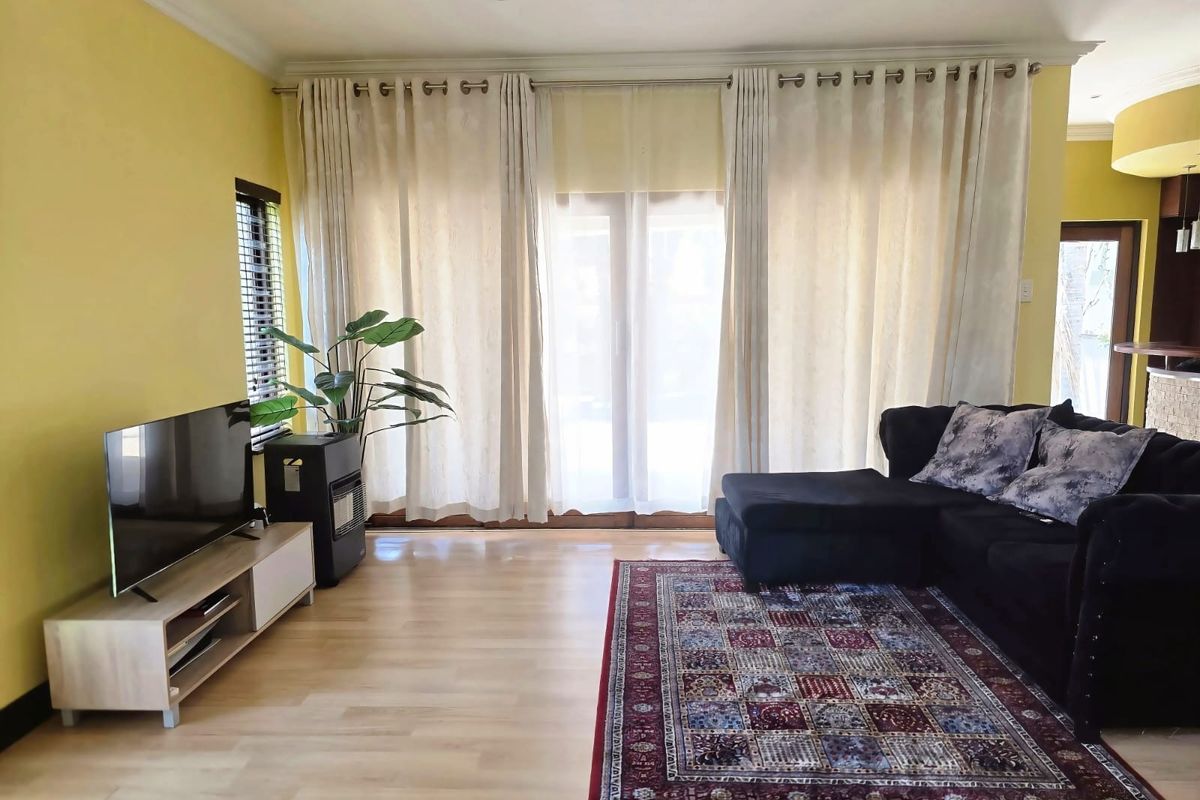 A bright living room featuring light laminate flooring, recessed ceiling lighting, and large sliding glass doors that provide access to the outdoor area.