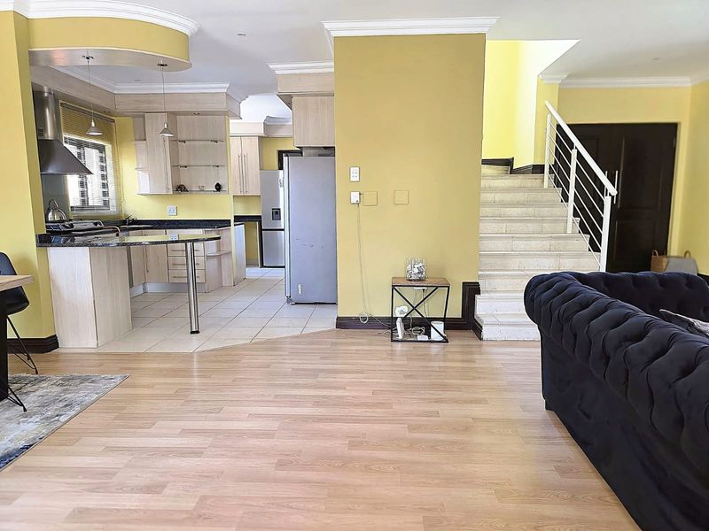 Open-plan living area featuring a kitchen with granite countertops, laminate flooring, and a staircase leading to the upper level.