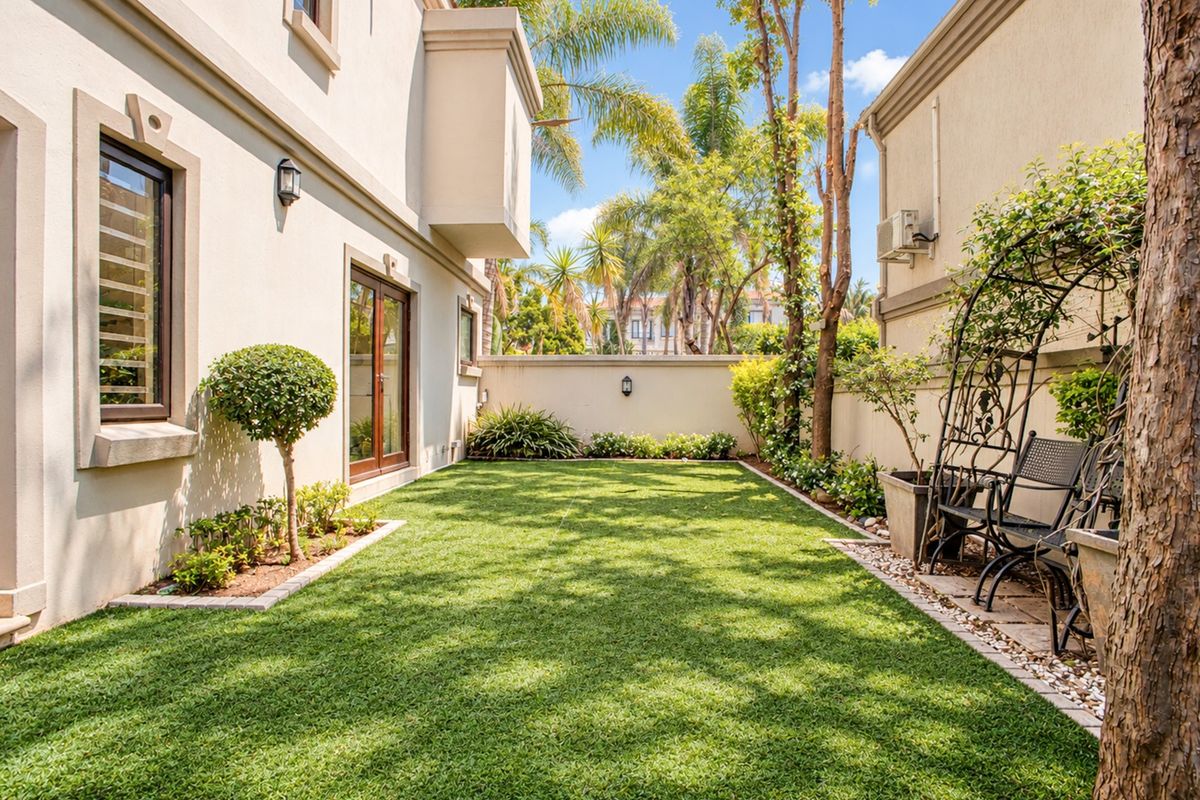 A well-maintained rear garden featuring a neat artificial lawn, perimeter boundary walls, and established landscaping, providing a private outdoor space.