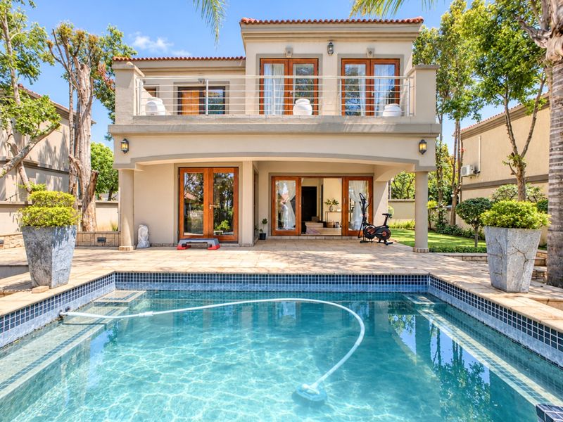 A well-maintained double-storey home featuring a private swimming pool, spacious tiled patio, and an upper-level balcony with wooden framed glass doors.