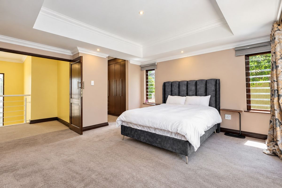Spacious bedroom featuring a tray ceiling, recessed lighting, built-in cupboards, and neutral carpeting, offering a comfortable and well-maintained living space.