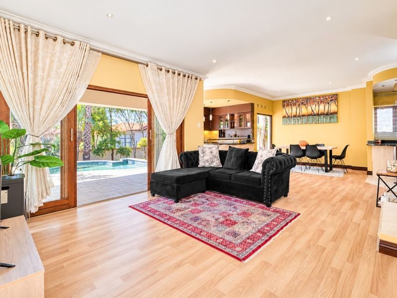 Spacious open-plan living and dining area featuring laminate flooring, recessed lighting, and large sliding doors opening onto a private pool patio.