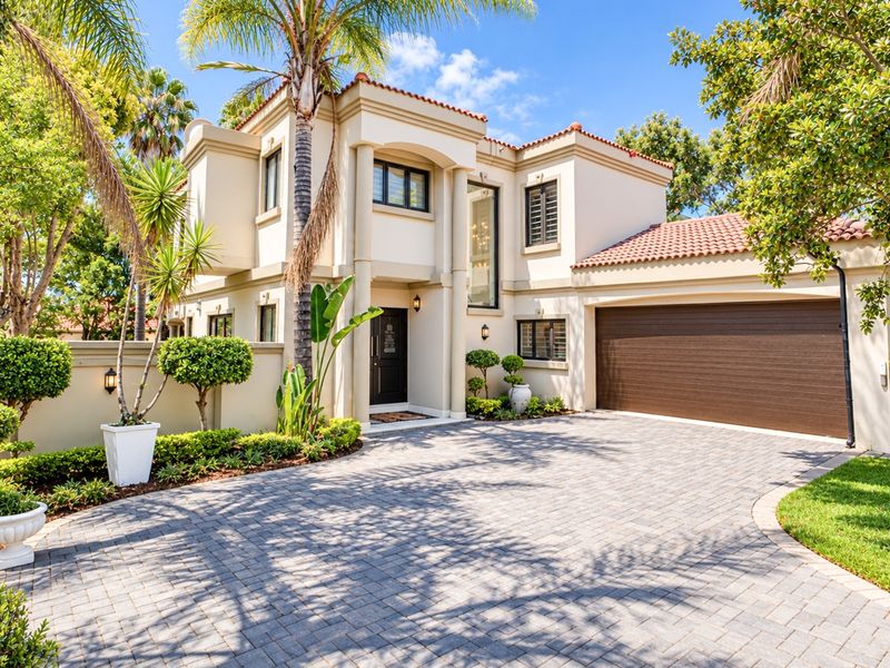 A well-maintained double-story residence featuring a paved driveway, integrated double garage, and attractive landscaped front garden with classic architectural detailing.