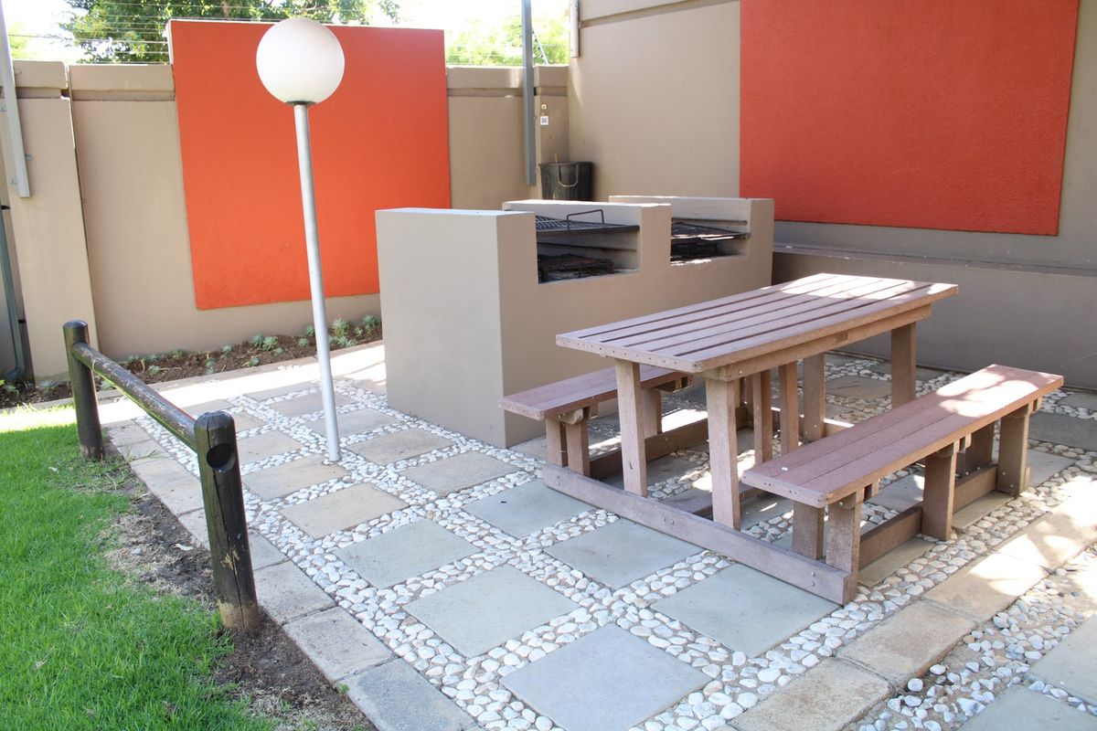 Outdoor entertainment area featuring a built-in braai, paved patio flooring, and a secure boundary wall with electric fencing.