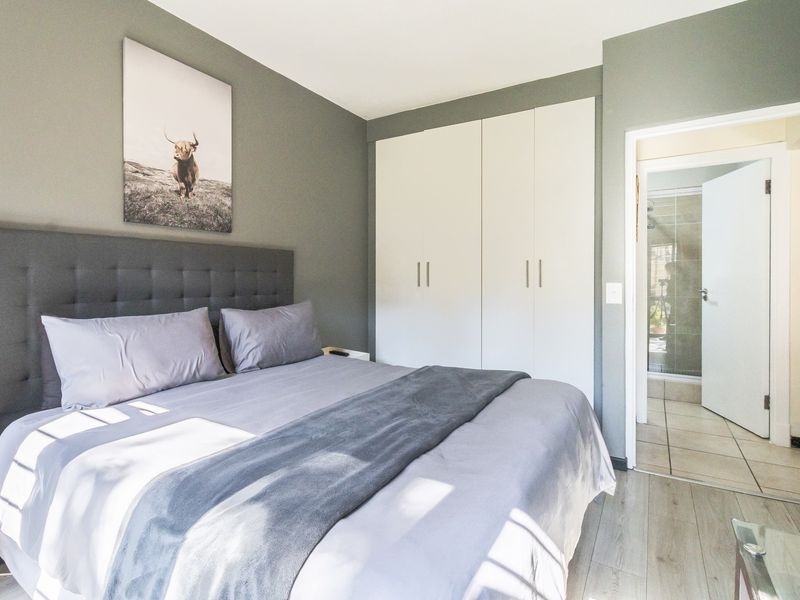 A well-maintained bedroom featuring modern laminate flooring, built-in cupboards, and direct access to an ensuite bathroom.