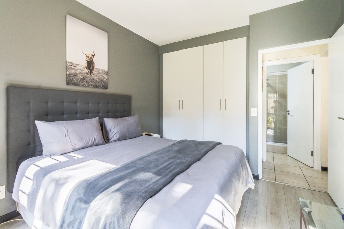 A well-maintained bedroom featuring modern laminate flooring, built-in cupboards, and direct access to an ensuite bathroom.