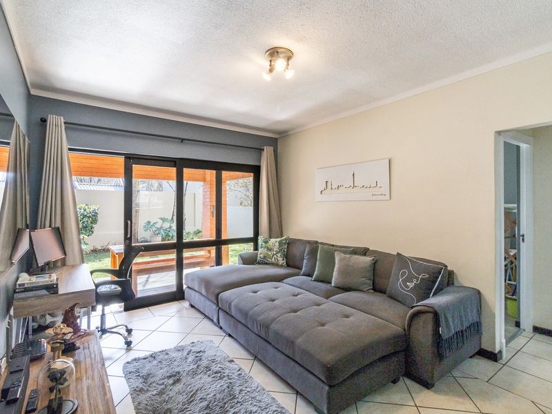 A well-maintained living room featuring tiled flooring and large sliding glass doors that provide direct access to the outdoor patio area.