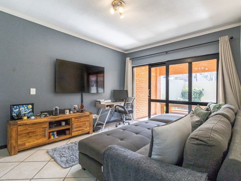 A comfortable living room featuring tiled flooring and a large sliding glass door that provides access to an outdoor patio area.