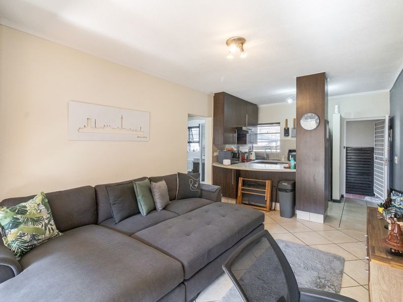 Open-plan living area featuring tiled flooring and a functional kitchen with built-in cabinetry and a breakfast counter.