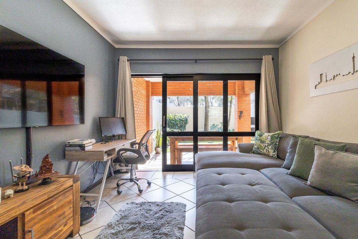 A comfortable living room featuring tiled flooring and a large sliding glass door that provides direct access to an outdoor patio area.