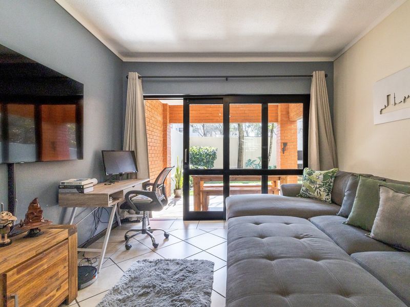 A comfortable living room featuring tiled flooring and a large sliding glass door that provides direct access to an outdoor patio area.