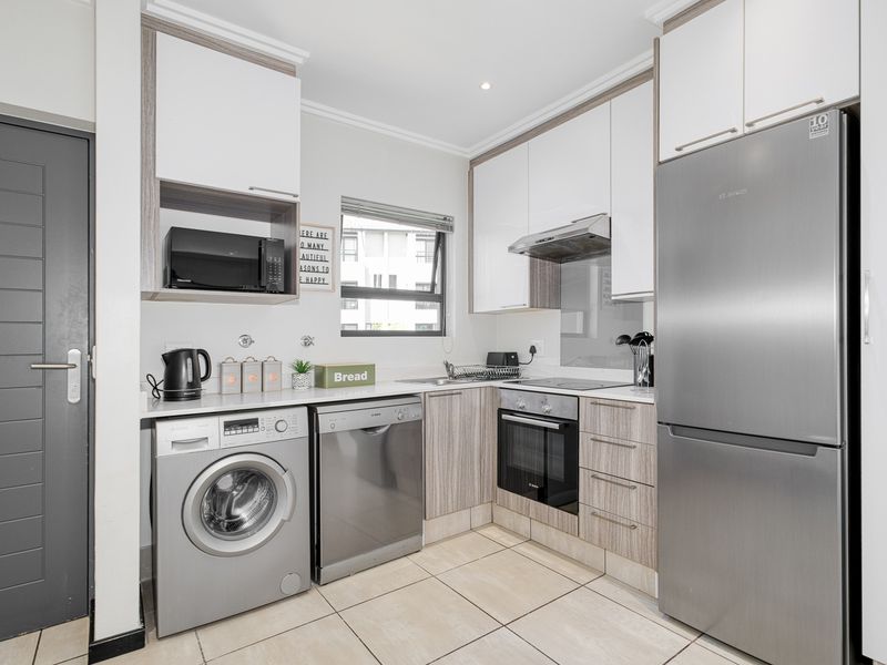 Modern kitchen featuring sleek cabinetry, integrated appliances, tiled flooring, and a functional layout with dedicated space for laundry and dishwasher units.
