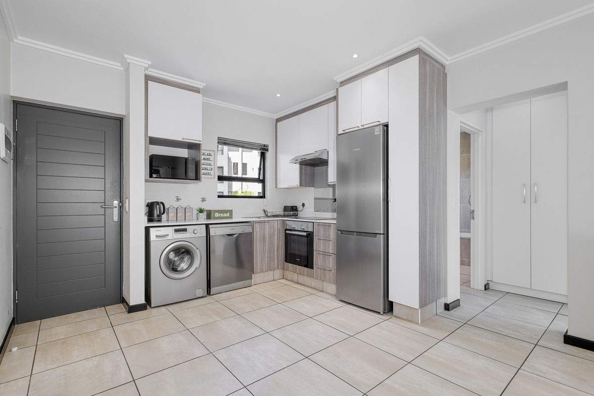 Modern kitchen featuring sleek built-in cabinetry, integrated appliances, tiled flooring, and a functional layout with direct access to adjacent living areas.