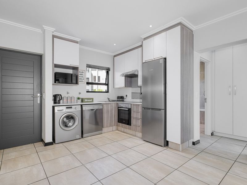 Modern kitchen featuring sleek built-in cabinetry, integrated appliances, tiled flooring, and a functional layout with direct access to adjacent living areas.