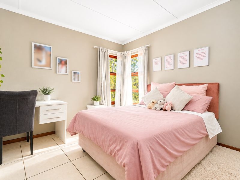 A well-maintained bedroom featuring neutral wall tones, tiled flooring, and corner windows that provide natural light.