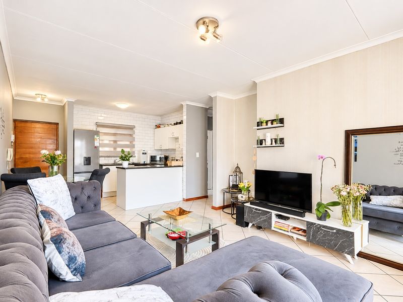 An open-plan living and kitchen area featuring tiled flooring, a kitchen island with a breakfast bar, and a subway tile backsplash.