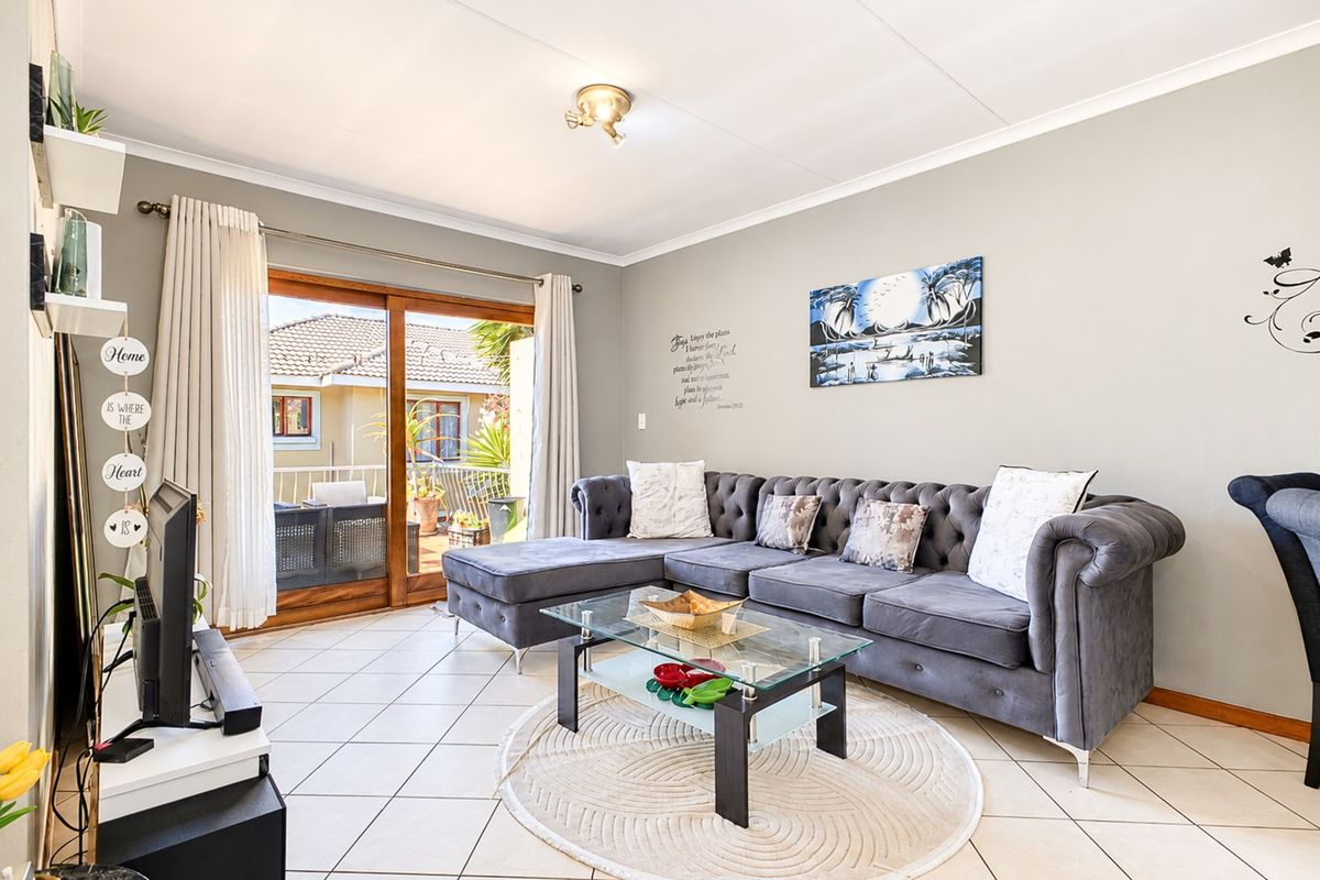 A bright living room featuring tiled flooring and a large sliding glass door that provides access to an outdoor patio area.