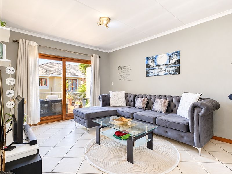 A bright living room featuring tiled flooring and a large sliding glass door that provides access to an outdoor patio area.