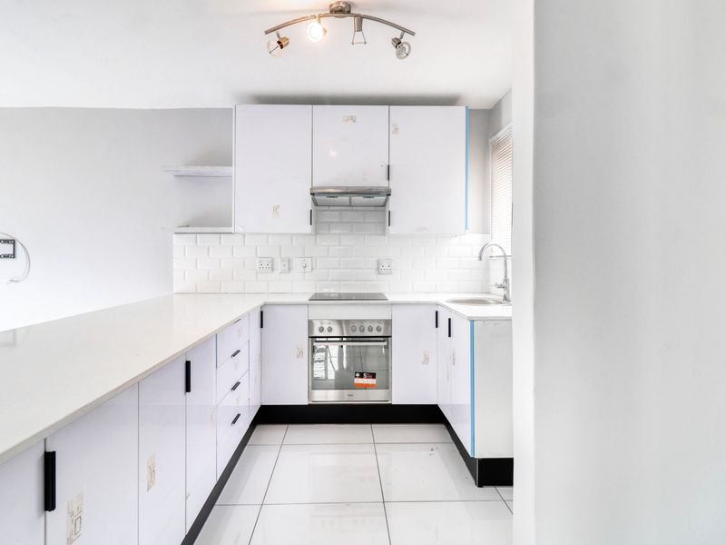 A clean, modern kitchen featuring white cabinetry, subway tile backsplash, quartz countertops, and integrated appliances, offering a bright and functional cooking space.