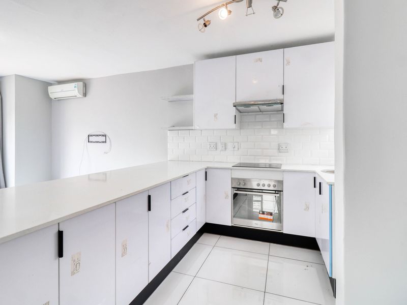 Modern kitchen featuring white cabinetry, subway tile backsplash, quartz countertops, and integrated appliances, including an electric hob and oven.
