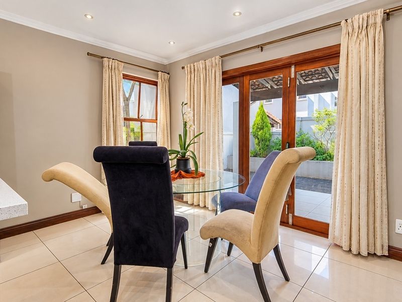 A bright dining area featuring tiled flooring, recessed lighting, and wooden framed glass sliding doors providing direct access to the outdoor patio.