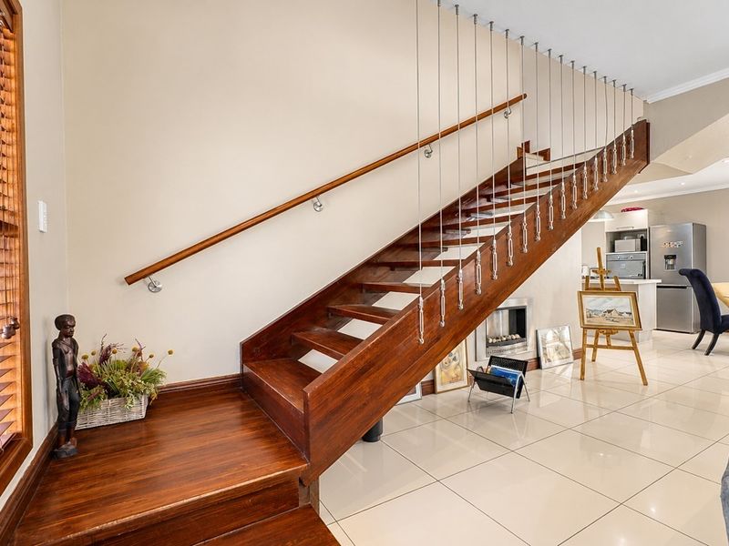 Open plan living area featuring a striking wooden staircase with modern cable balustrades, tiled flooring, and a built-in fireplace.
