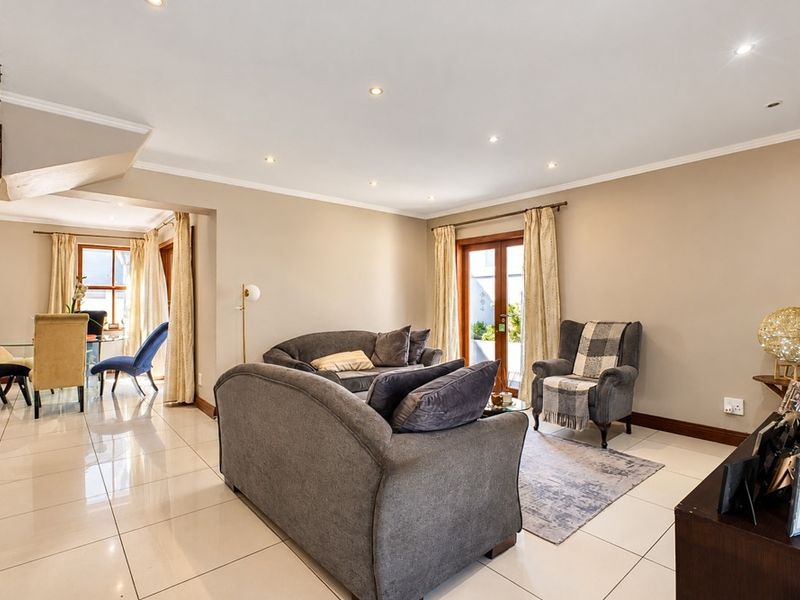 Spacious open-plan living and dining area featuring polished tiled floors, recessed lighting, and direct access to the patio through double glass doors.
