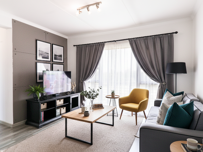 A well-lit living room featuring modern laminate flooring, a decorative feature wall, and large sliding glass doors that provide ample natural light.