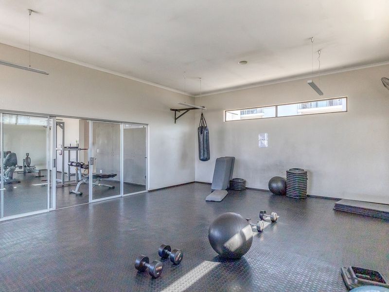A spacious gym area featuring durable rubber flooring, sliding glass doors, and high-level clerestory windows providing natural light.