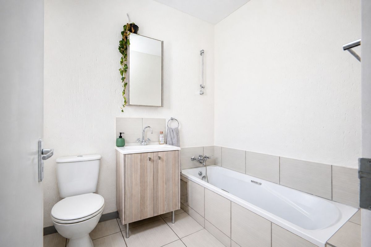 A clean and functional bathroom featuring a vanity unit, toilet, and a bathtub with tiled splashbacks.