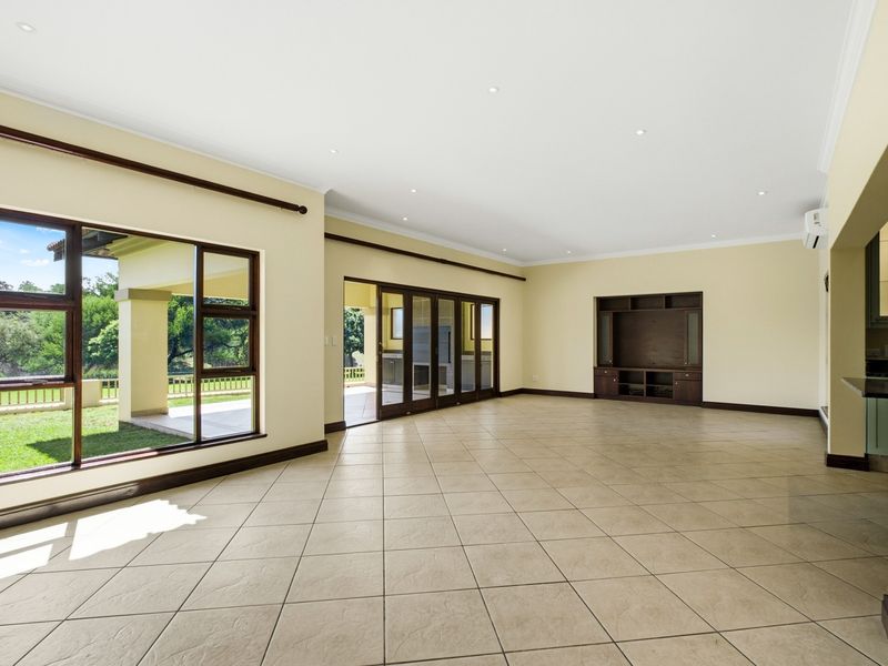 Spacious, light-filled living area featuring neutral tiled floors, recessed lighting, a built-in media unit, and large sliding doors opening to the outdoor patio.