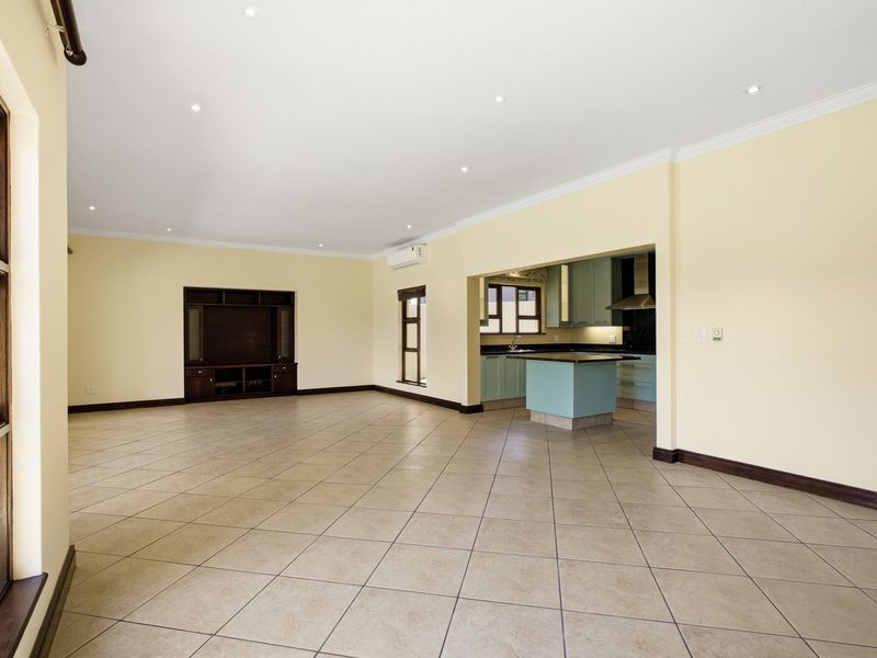 Spacious open-plan living area featuring tiled floors, recessed lighting, and a functional kitchen with built-in cabinetry and an island.