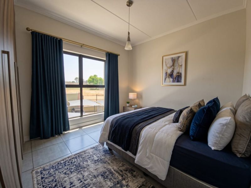 A well-maintained bedroom featuring tiled flooring, a large window with natural light, and built-in wardrobe storage.