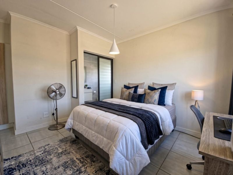 A well-lit bedroom featuring tiled flooring, a neutral color palette, and an integrated en-suite bathroom with a sliding door.