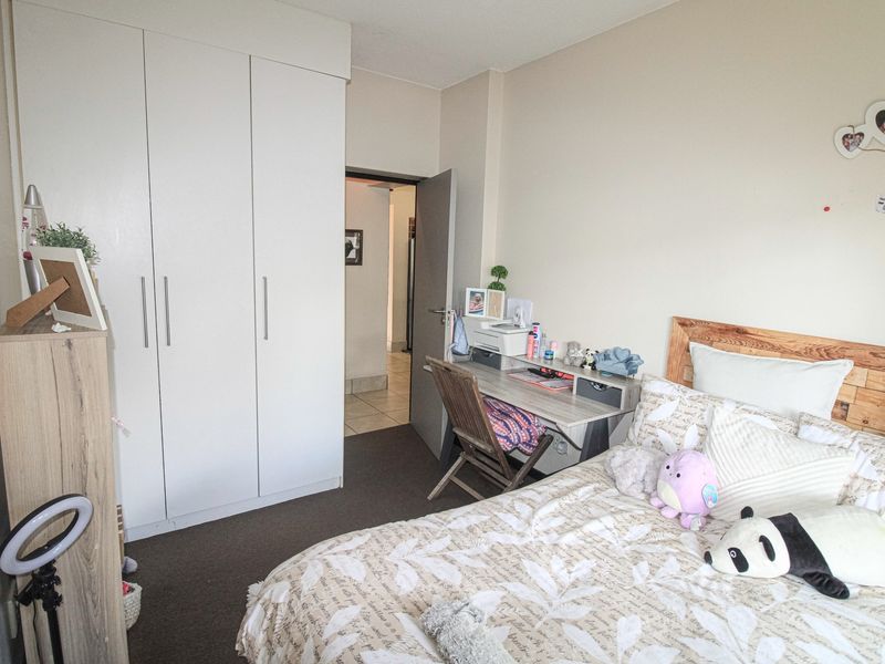 A functional bedroom featuring built-in cupboards and neutral wall finishes, providing a comfortable and practical living space.