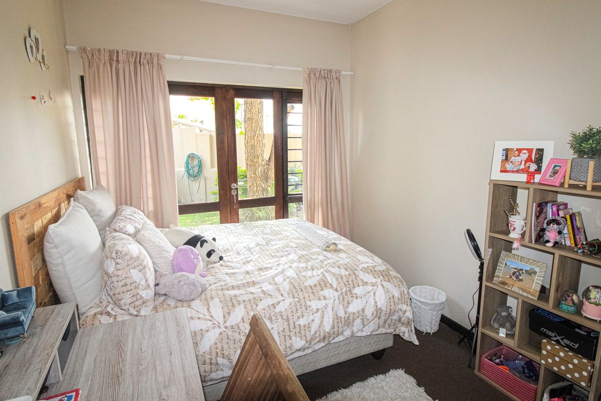 A cozy bedroom featuring carpeted flooring and a wooden framed glass door providing direct access to the exterior.