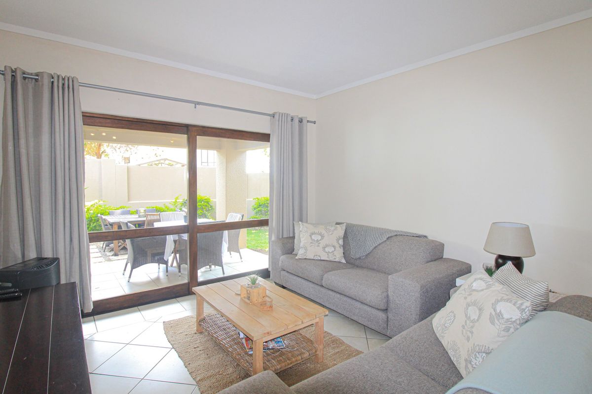 Bright living room featuring ceramic floor tiles and a large sliding glass door providing direct access to the outdoor patio area.