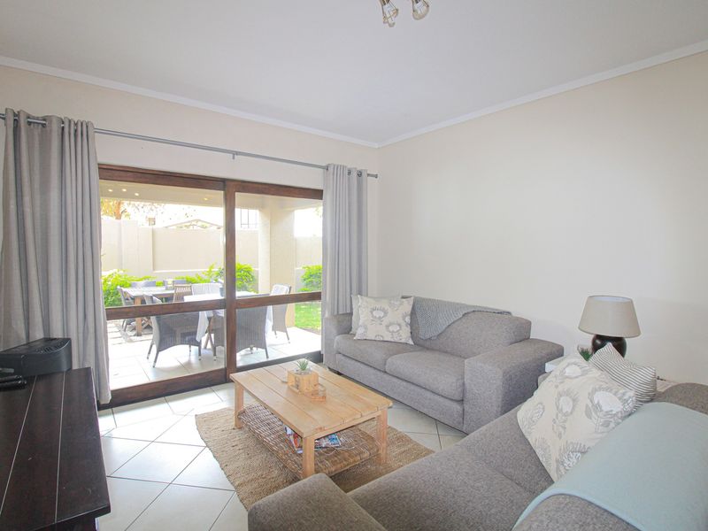 Bright living room featuring ceramic floor tiles and a large sliding glass door providing direct access to the outdoor patio area.